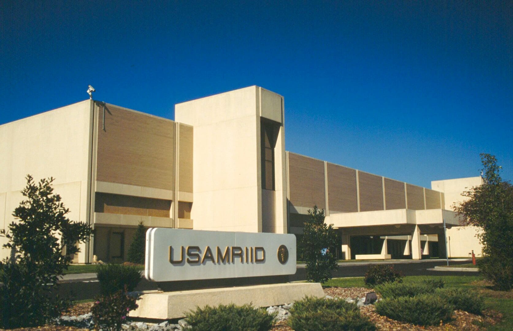 Photo of a building with USAMRIID displayed on a pedestal in front. 